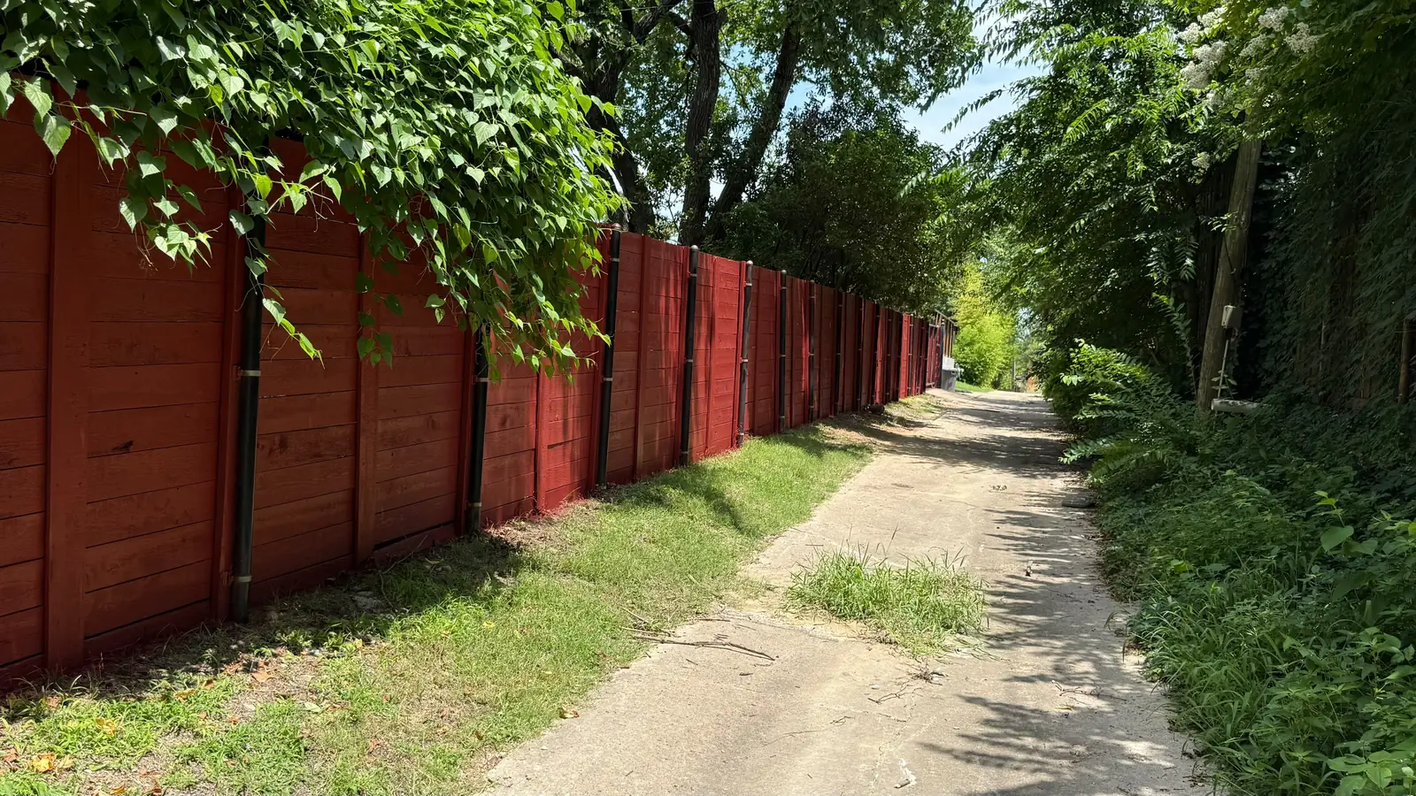 Dark red horizontal-board fence along an alley