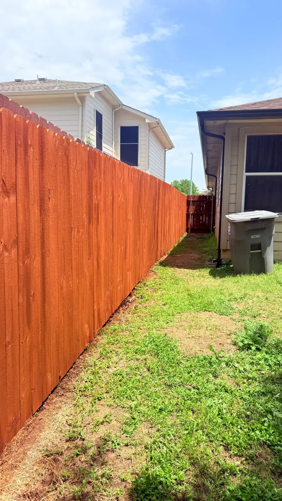 Stained stockade fence along a side yard
