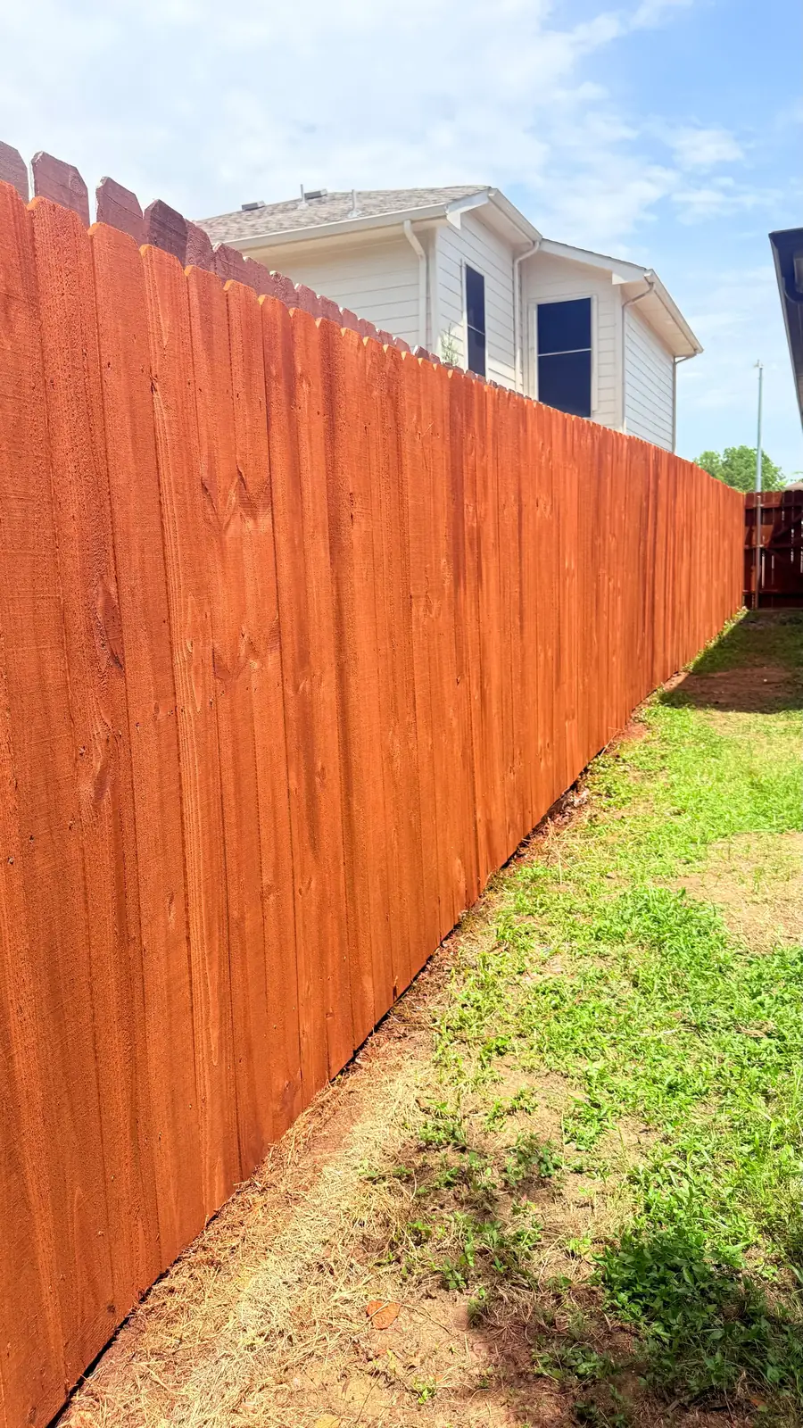 Red-orange stained stockade fence